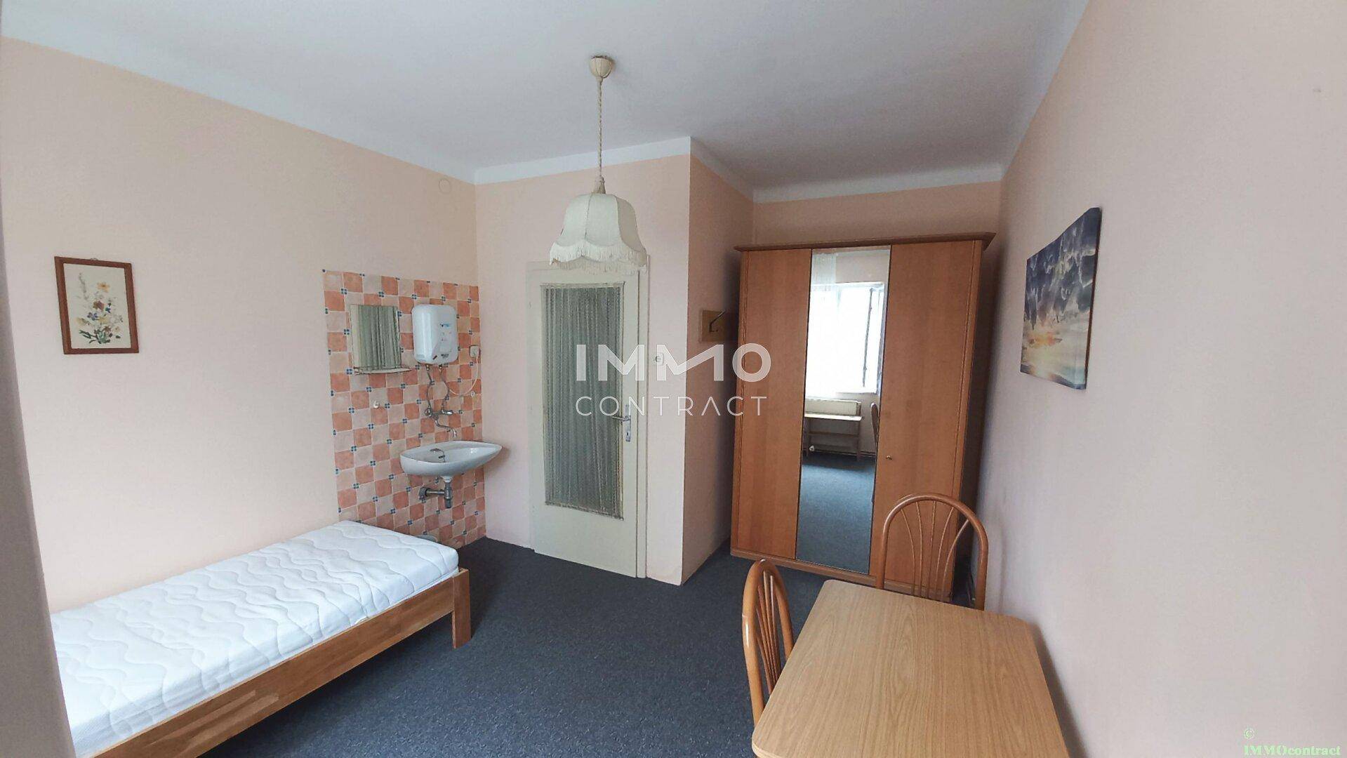 Schlafzimmer mit Einzelbett, Kleiderschrank und einem integrierten Waschbeckenbereich.