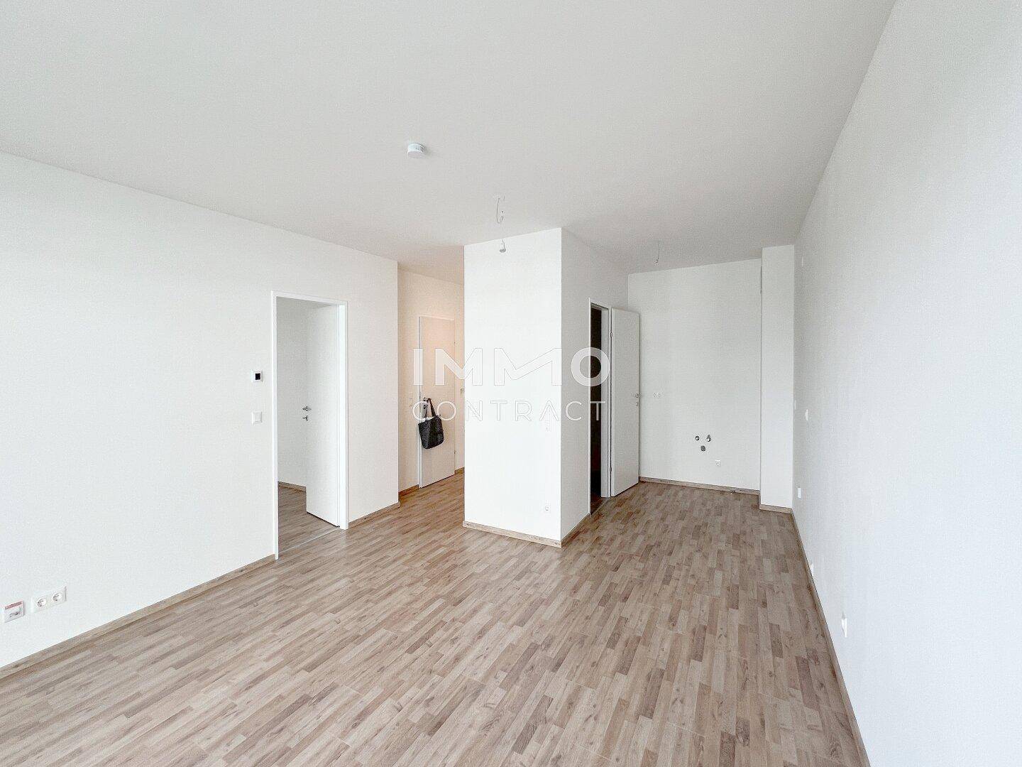 Helles Wohnzimmer mit Laminatboden und mehreren Türöffnungen zu angrenzenden Räumen.