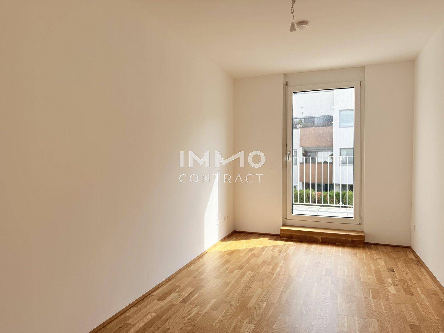Sonniger Raum mit Holzboden und Zugang zu einem französischen Balkon, perfekt als Schlafzimmer.