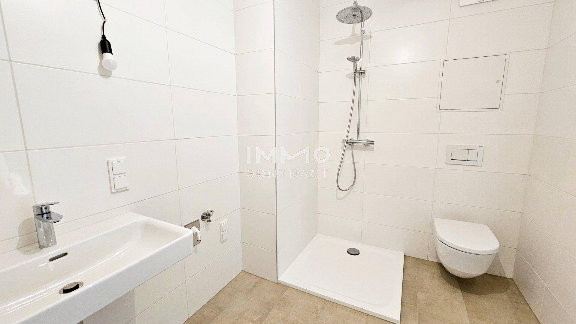 Helles Badezimmer mit weißen Fliesen, ebenerdiger Dusche und wandhängendem WC, modern und funktional gestaltet.