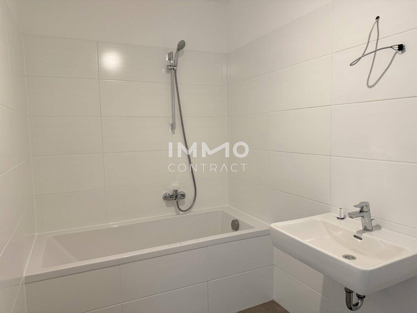 Modernes Badezimmer mit weiß gefliesten Wänden, Badewanne und Waschbecken.