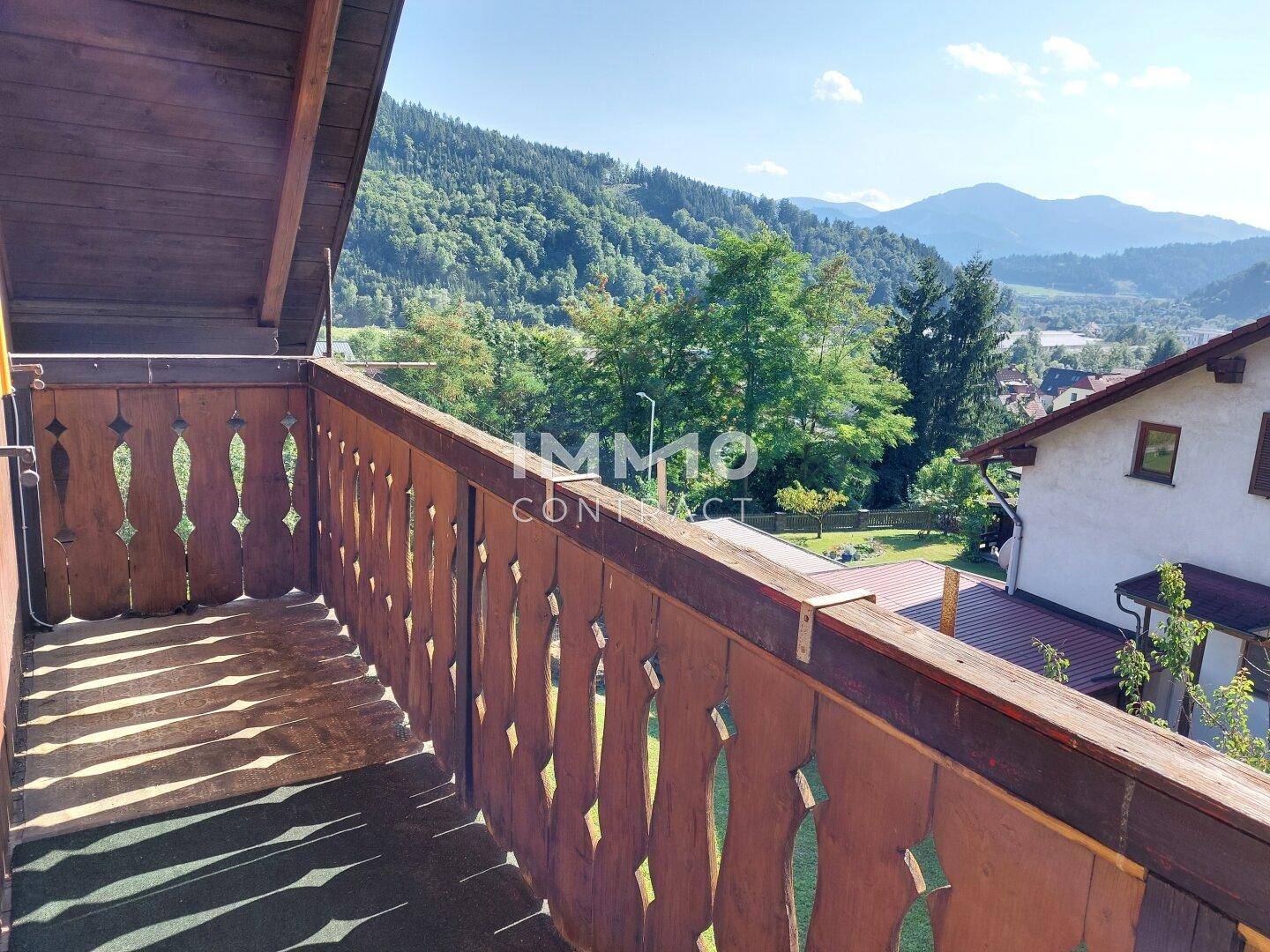 Balkon mit Holzbalkongeländer und atemberaubendem Blick auf die umliegende Berglandschaft.