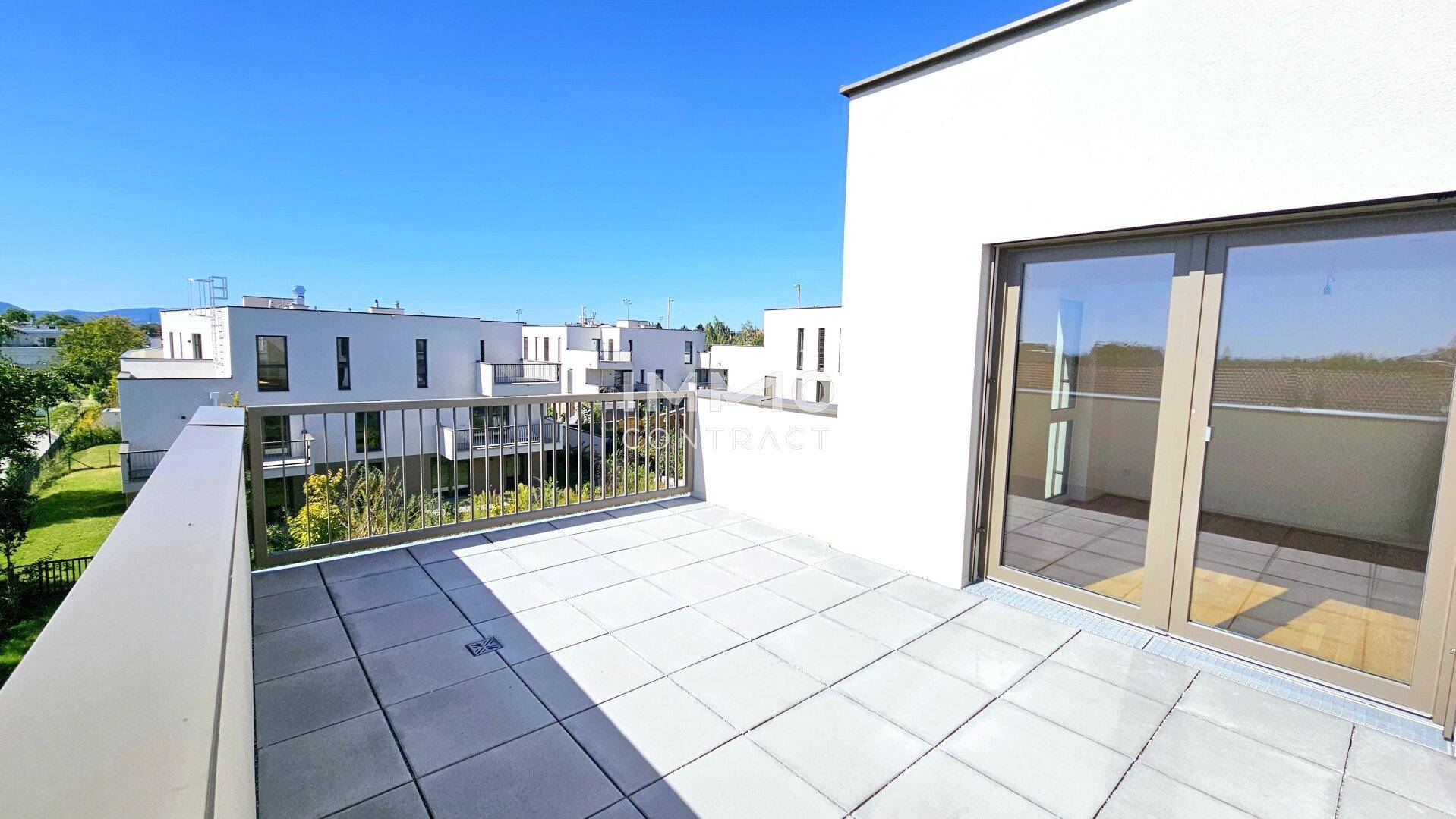 Sonniger Balkon mit Fliesenboden und Metallgeländer, bietet einen weiten Blick auf die umliegenden Gebäude.