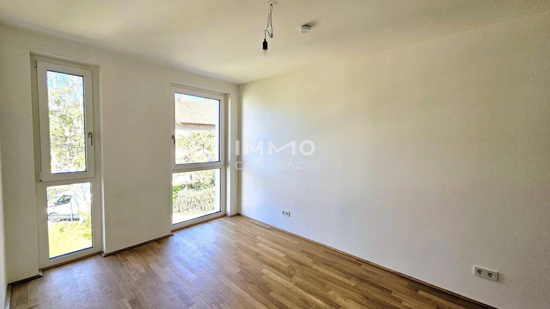 Helles Zimmer mit Holzboden und hohen Fenstern, die viel Licht hereinlassen und eine angenehme Atmosphäre schaffen.