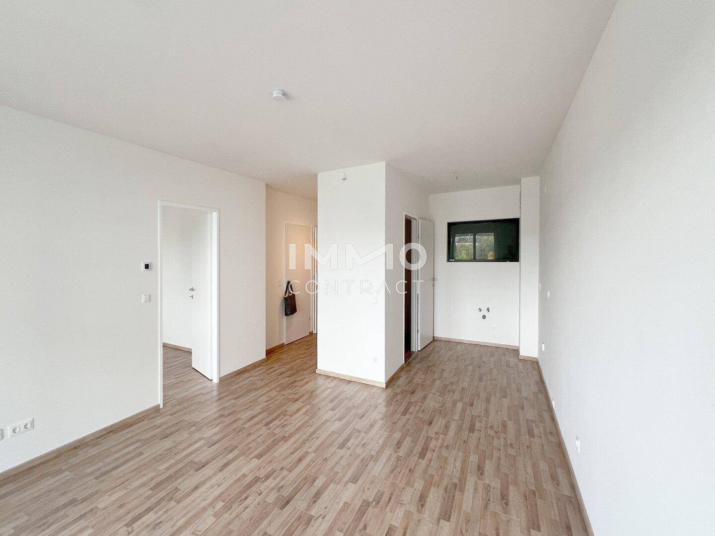 Geräumiger, heller Innenraum mit Laminatboden und weißen Wänden, bereit zur individuellen Gestaltung.