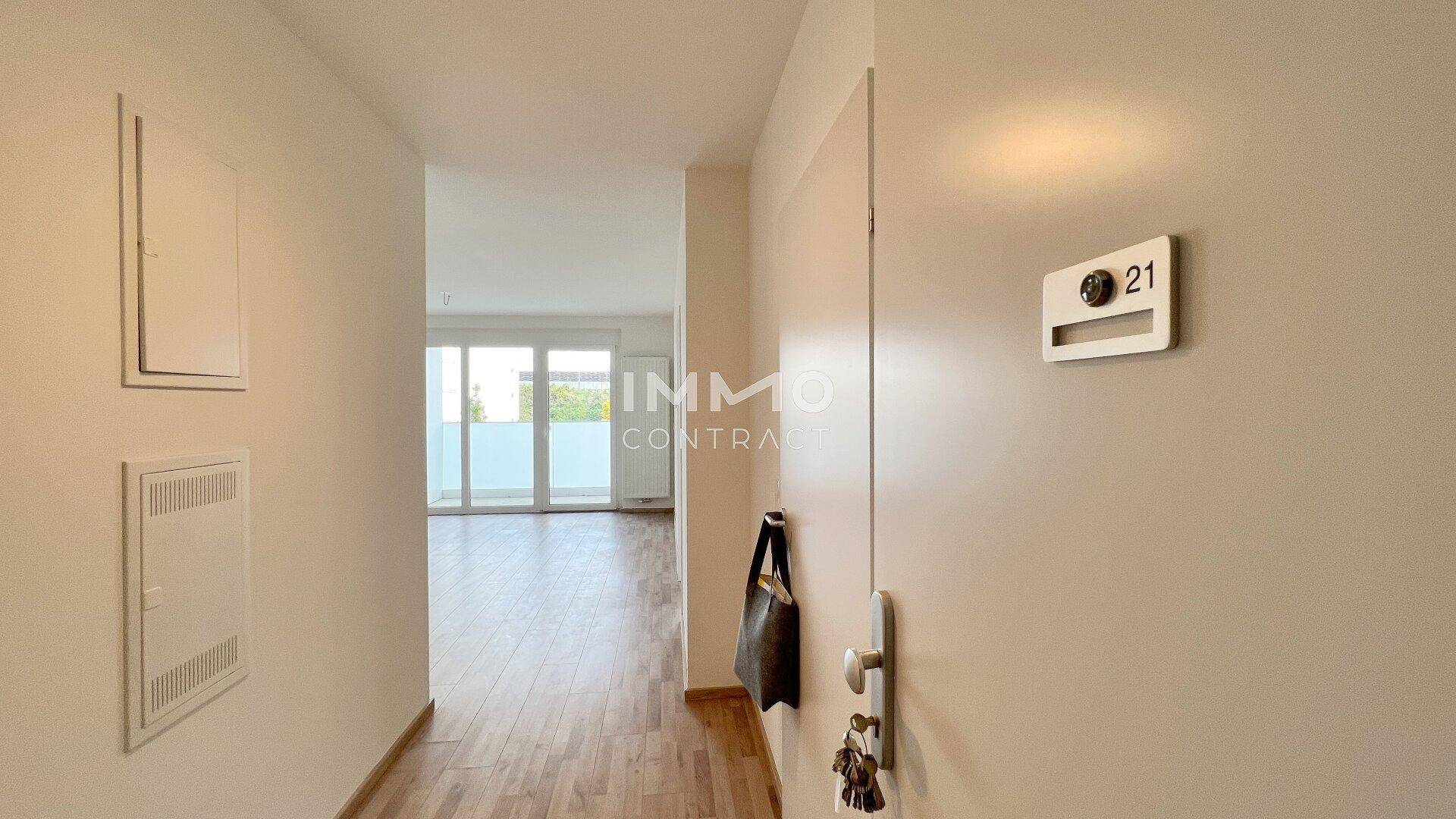 Heller Eingangsbereich mit Laminatboden und Blick in den Wohnbereich mit Balkonzugang.