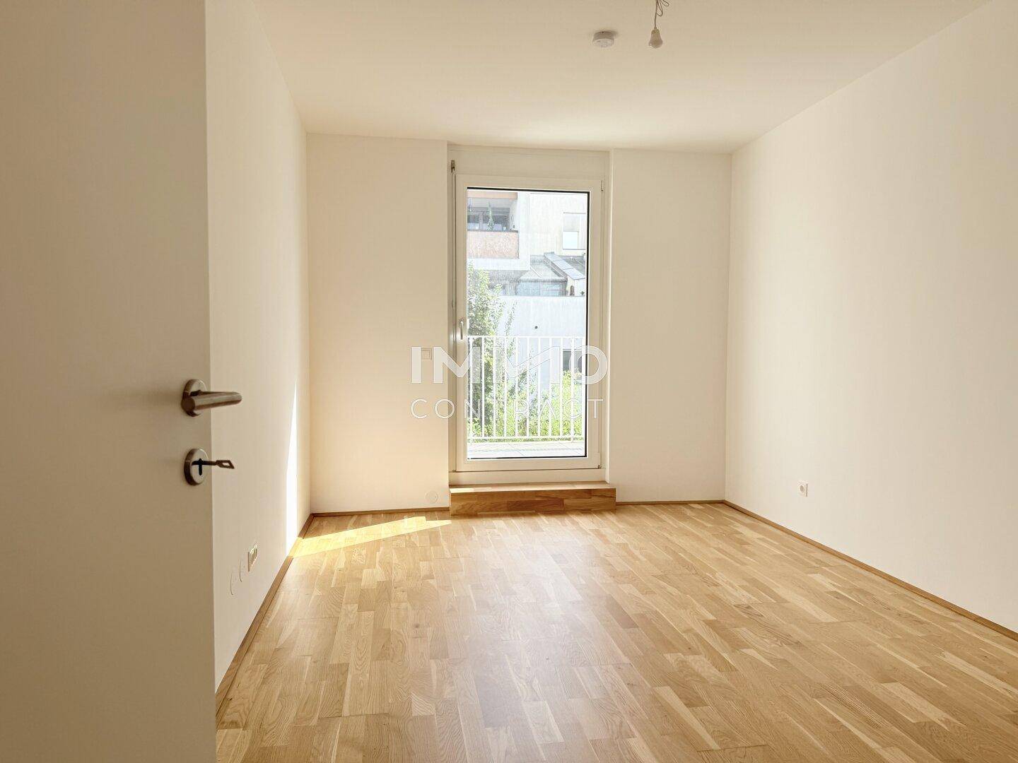 Helles Zimmer mit Parkettboden und Zugang zu einem französischen Balkon, ideal als Schlafzimmer.