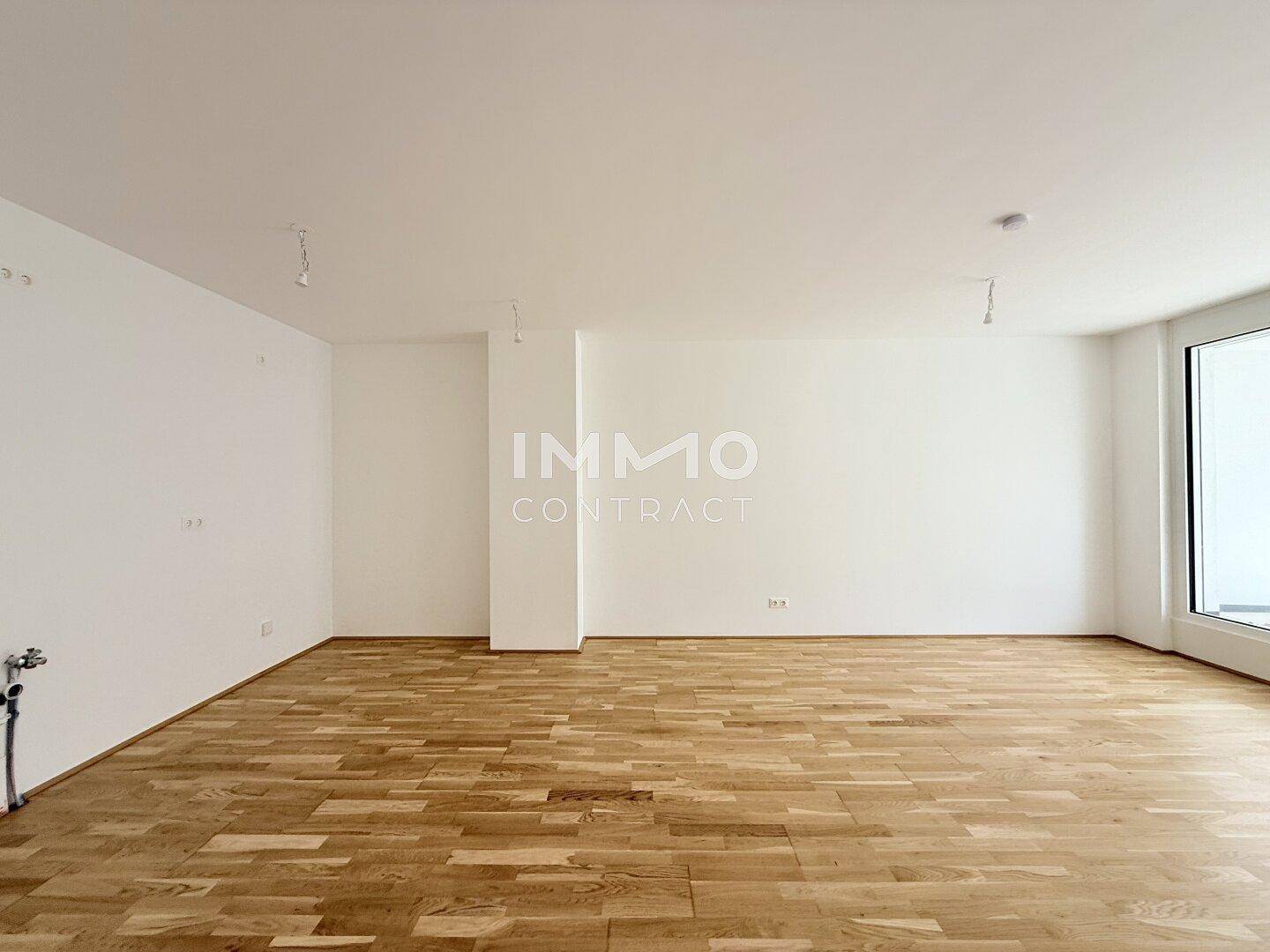 Geräumiger, heller Raum mit Parkettboden und großen Fenstern, ideal für einen Wohn- oder Essbereich.