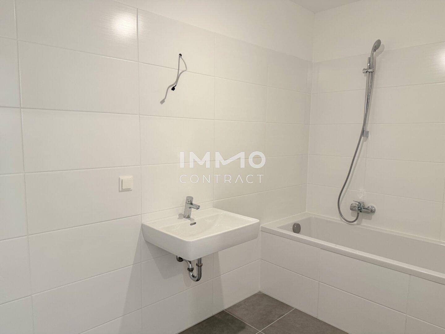 Modernes Badezimmer mit Badewanne, Waschbecken und weißen Wandfliesen.
