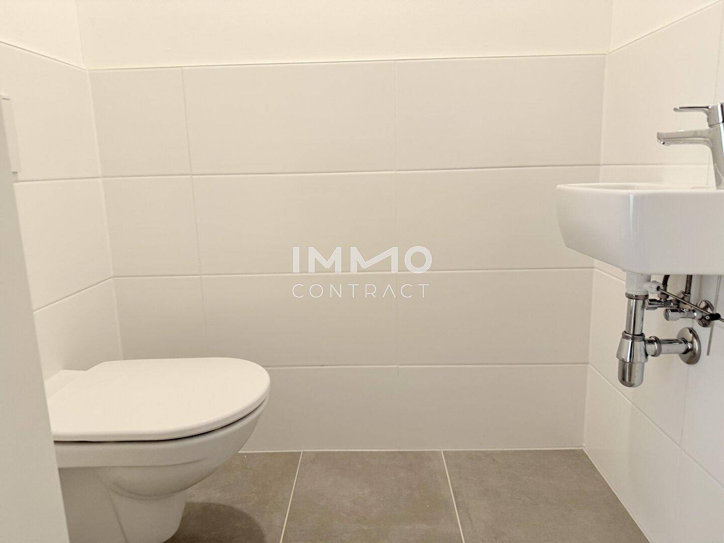 Separates WC mit wandhängender Toilette und kleinem Handwaschbecken.