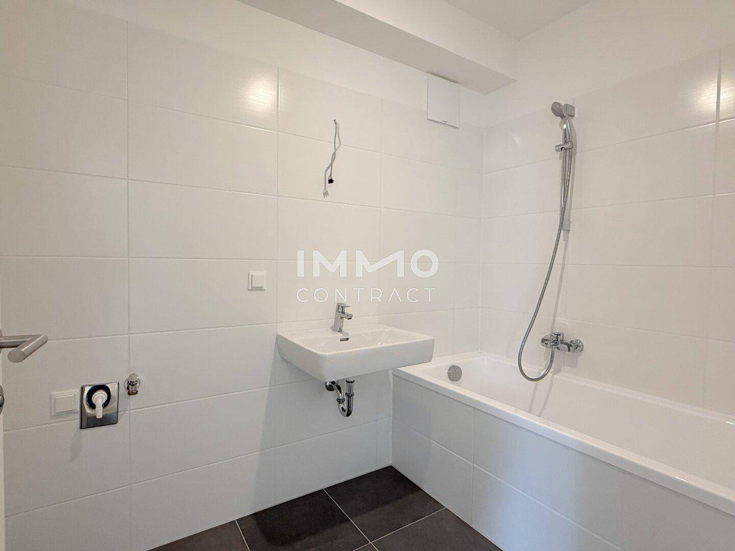 Modernes Badezimmer mit weißen Fliesen, Badewanne und einem einzelnen Waschbecken.
