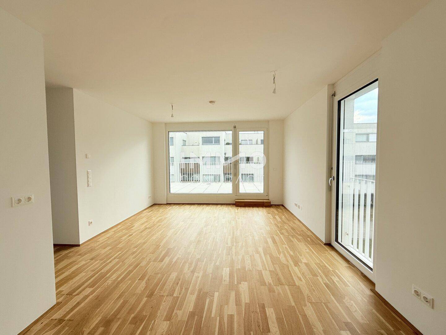 Geräumiges, helles Zimmer mit Parkettboden und großen Fenstern, die viel Tageslicht hereinlassen.