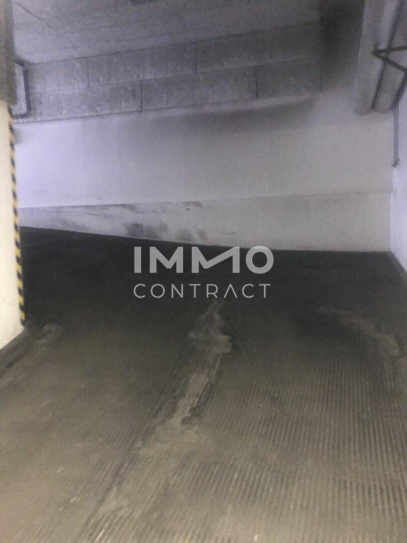 Zufahrtsbereich einer Tiefgarage mit Betonwänden und dunklem, strukturiertem Bodenbelag.