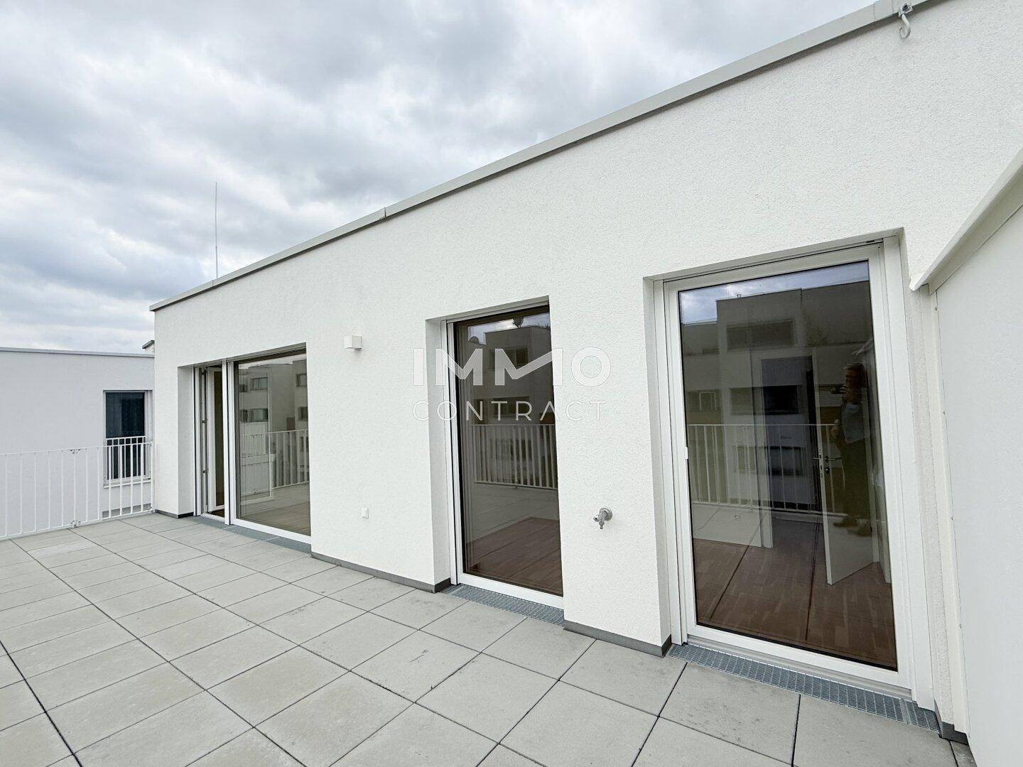 Weitläufige Dachterrasse mit mehreren Zugängen zu den Innenräumen und Blick auf die Umgebung.