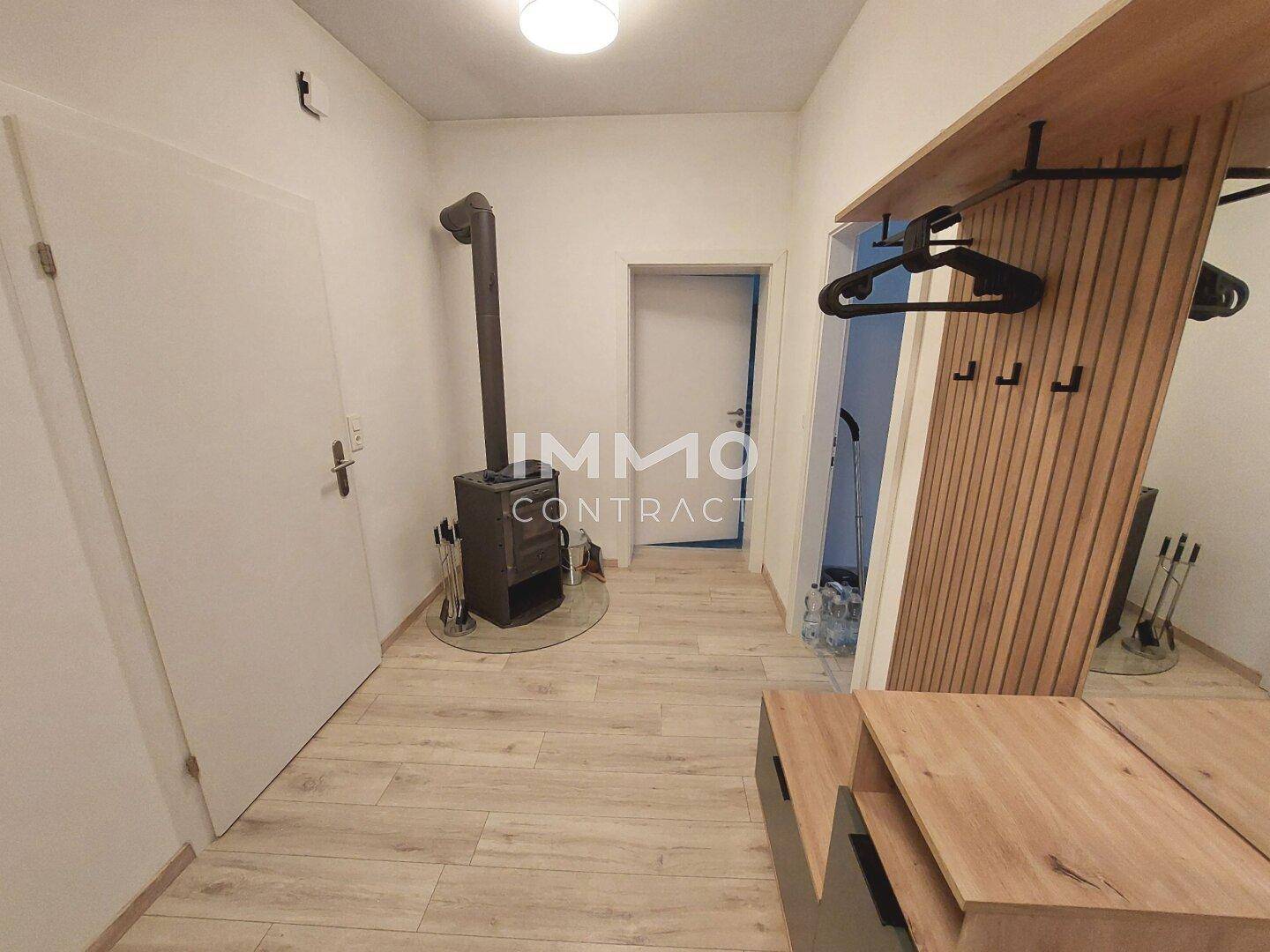 Eingangsbereich mit Holzofen, Garderobe und hellem Laminatboden.