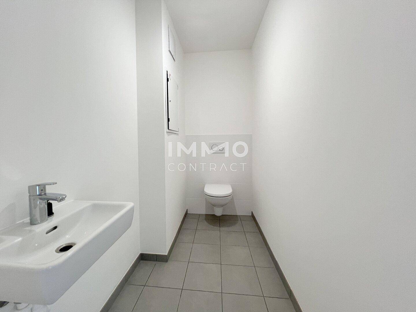 Modernes Gäste-WC mit Wand-WC und kleinem Waschbecken, gefliestem Boden.