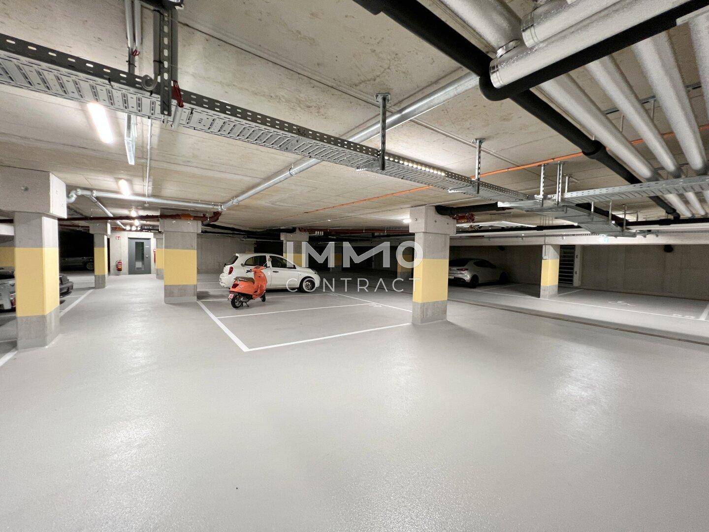 Tiefgarage mit markierten Stellplätzen und guter Beleuchtung, bietet sichere Parkmöglichkeiten.