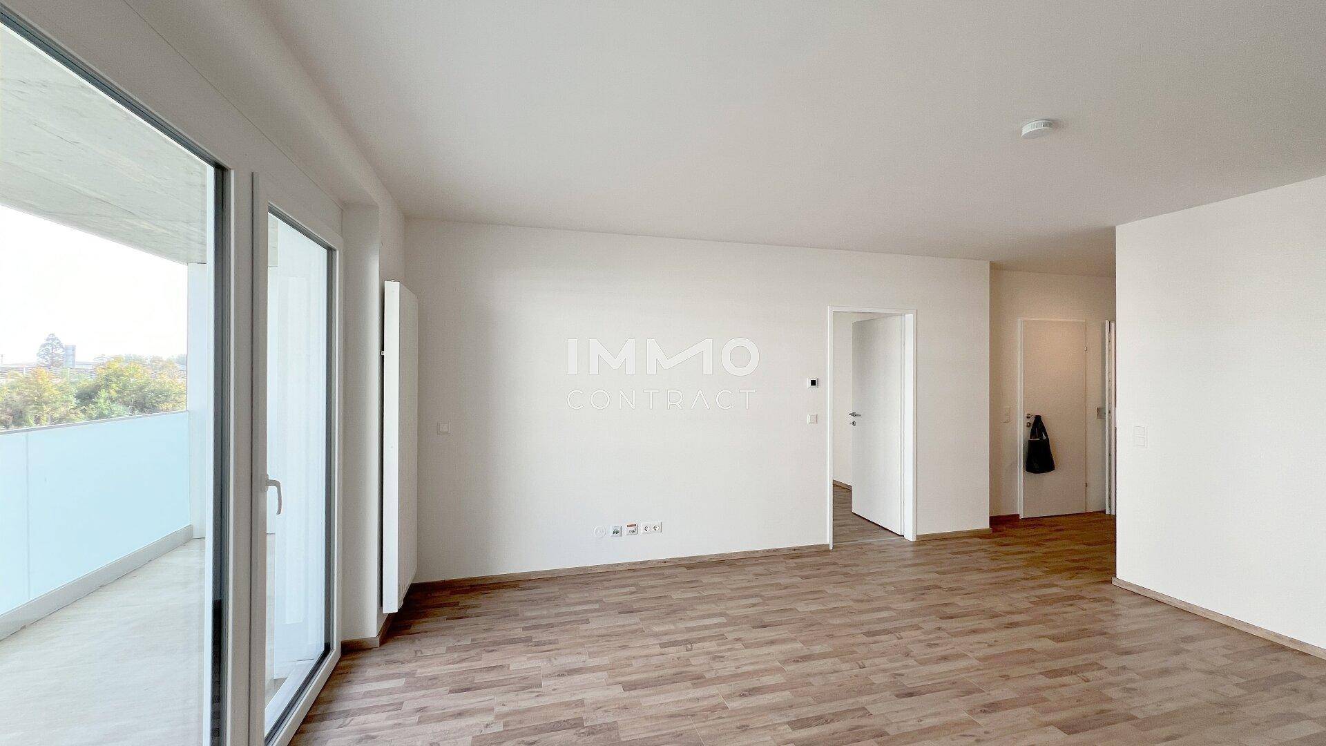 Lichtdurchflutetes Wohnzimmer mit Laminatboden und direktem Zugang zum großzügigen Balkon.