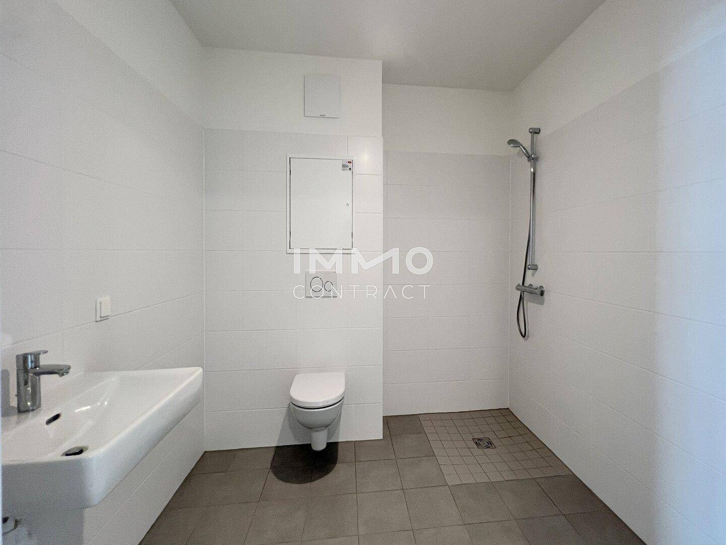 Modernes Badezimmer mit Dusche, wandhängendem WC und weißen Fliesen, in sehr gutem Zustand.