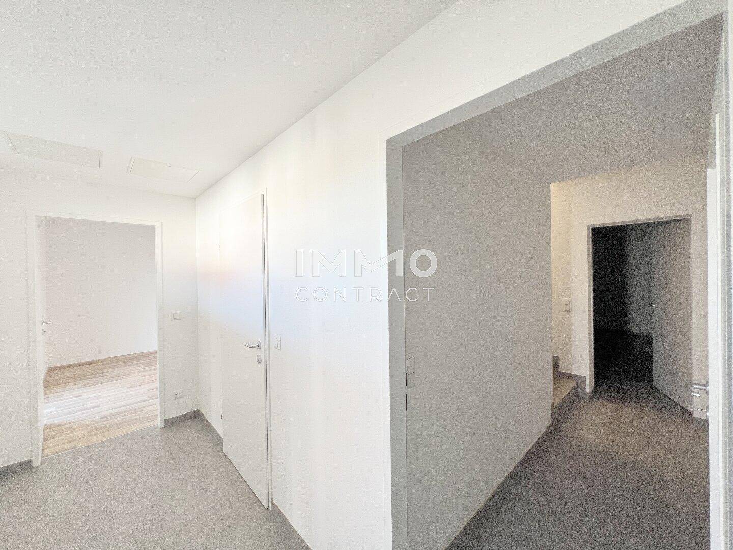Flur mit Fliesenboden und weißen Türen, der verschiedene Bereiche des Hauses verbindet.
