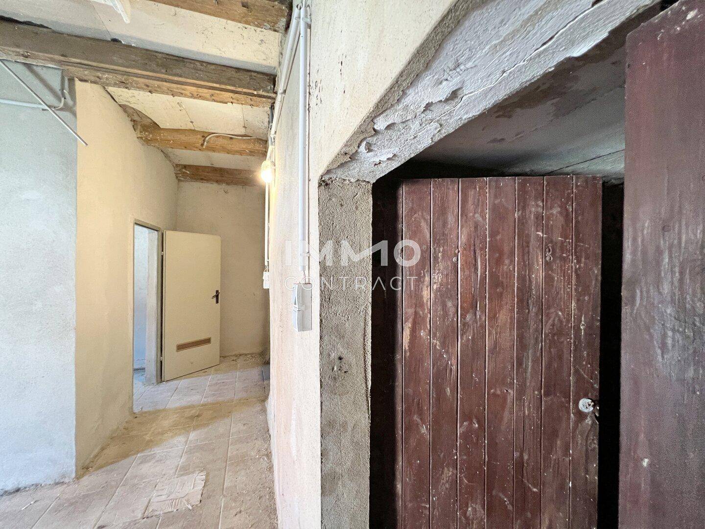 Alter Raum mit sichtbaren Holzbalken und einer weiteren Holztür, die den rustikalen Charme unterstreicht.