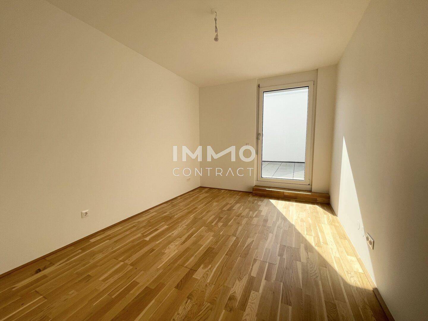Gemütliches Zimmer mit Holzboden und einer Fenstertür, die auf die Terrasse führt.