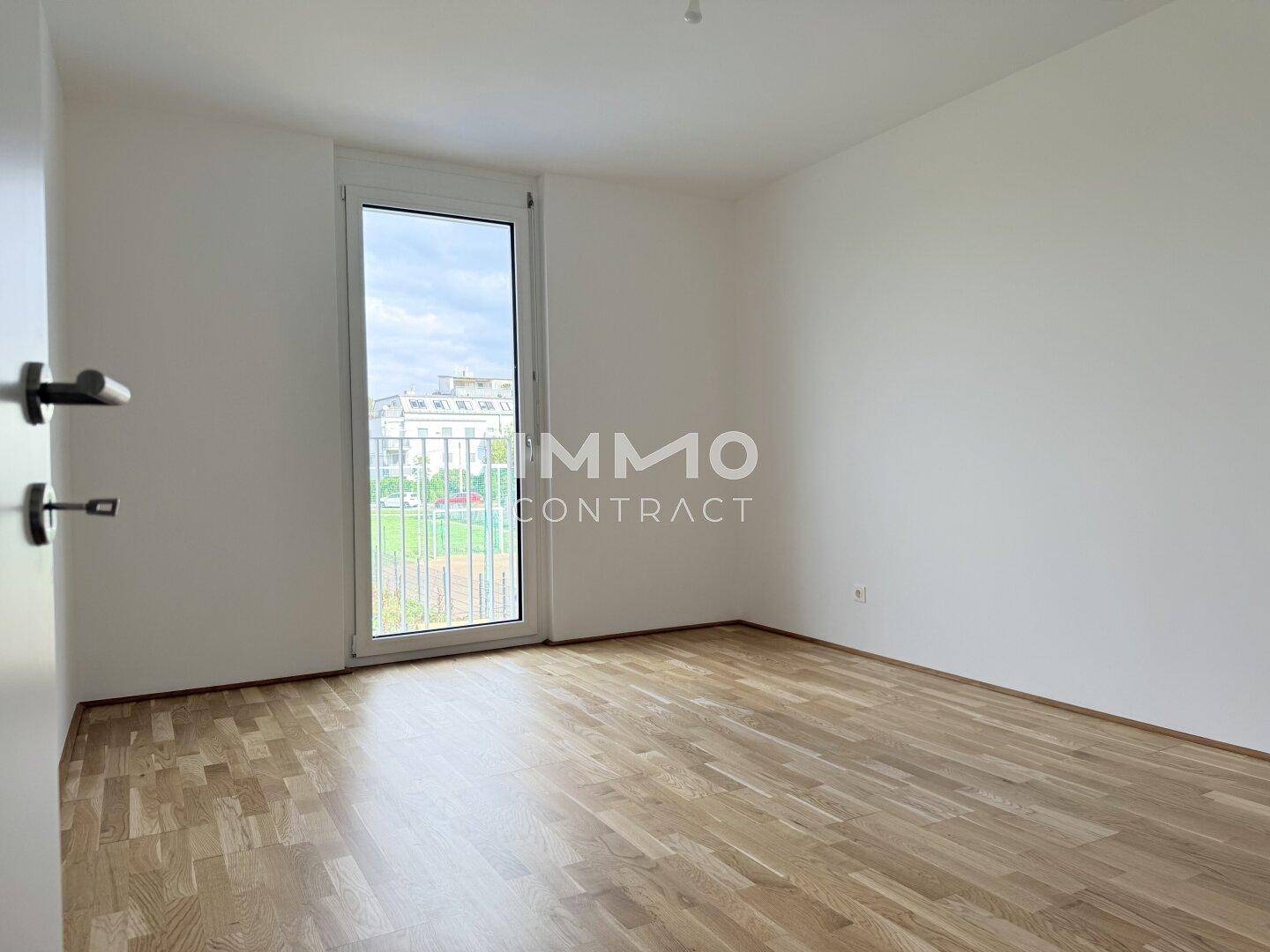 Helles Schlafzimmer mit Parkettboden und Fenster mit französischem Balkon.