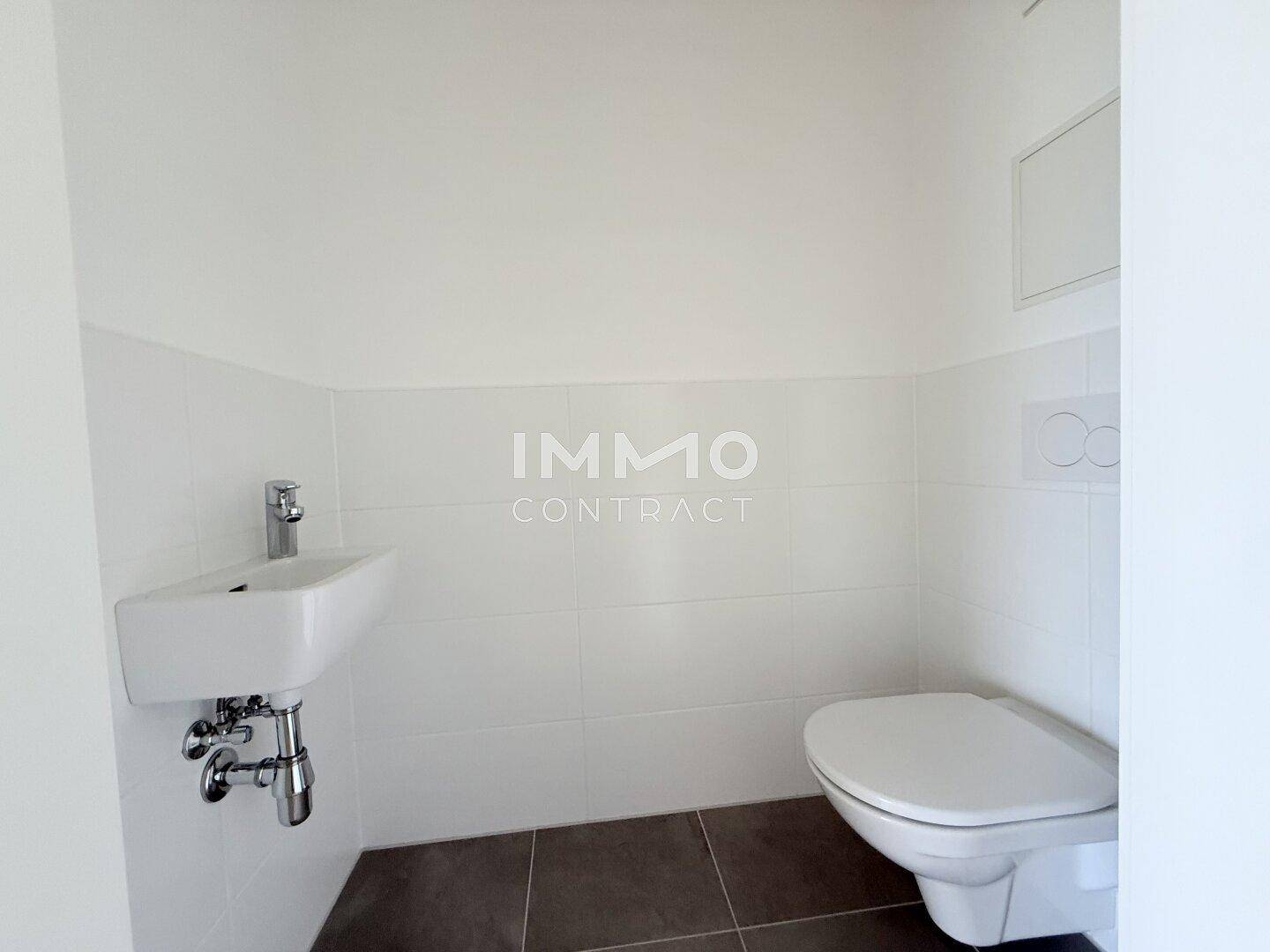 Separates WC mit wandhängender Toilette und kleinem Waschbecken.