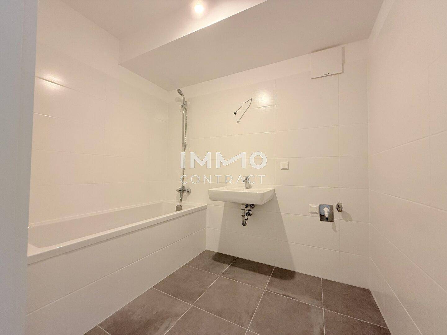 Modernes Badezimmer mit Badewanne, Waschbecken und hellen Fliesen.