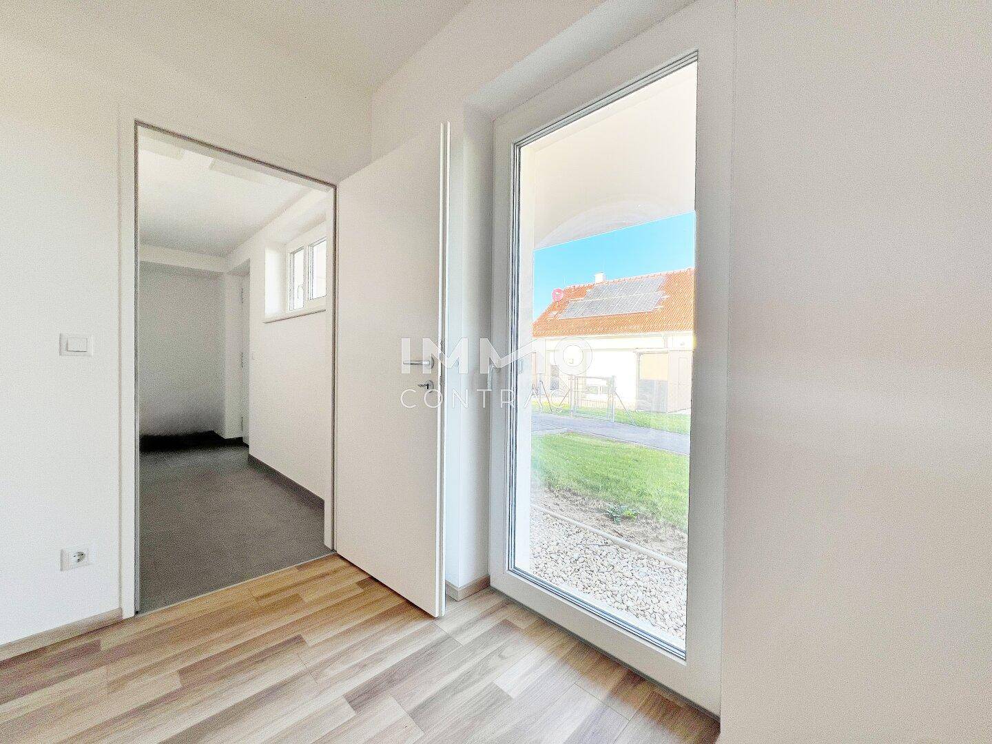 Heller Raum mit Zugang zum Garten und einer weiteren Tür, ideal als Schlaf- oder Arbeitszimmer.
