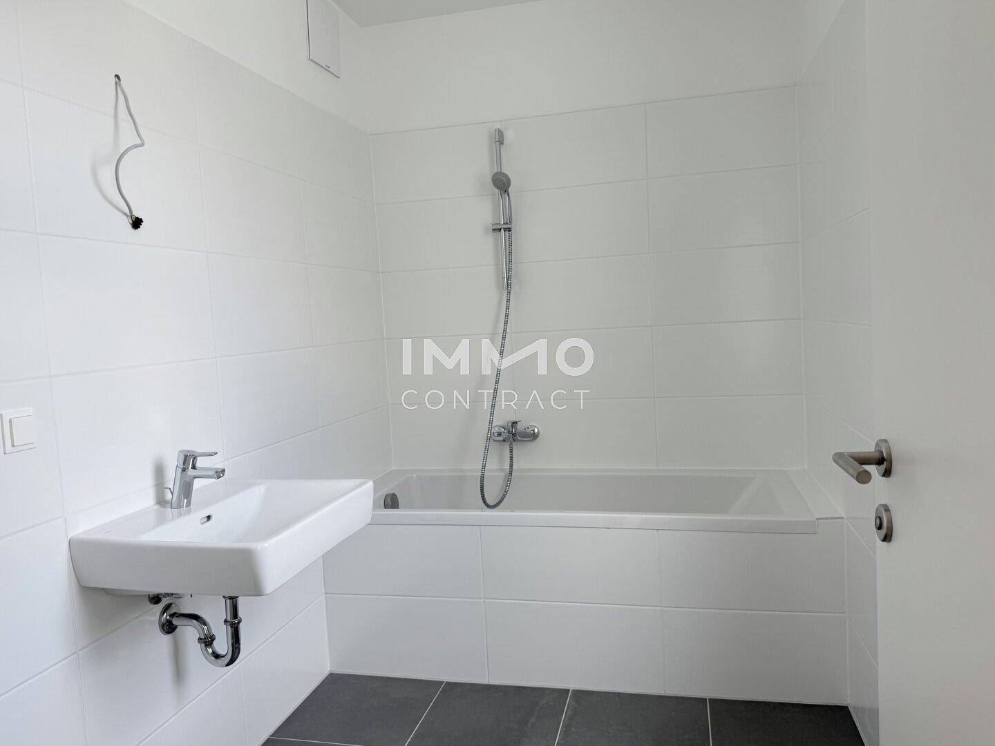 Modernes Badezimmer mit Badewanne, Waschbecken und weißen Fliesen.