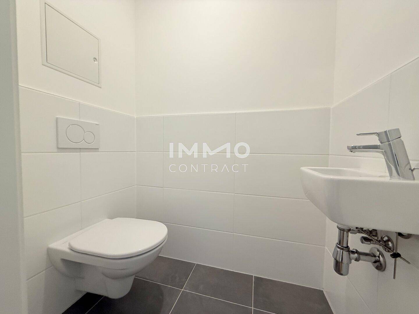 Separates Gäste-WC mit wandhängender Toilette und kleinem Waschbecken.