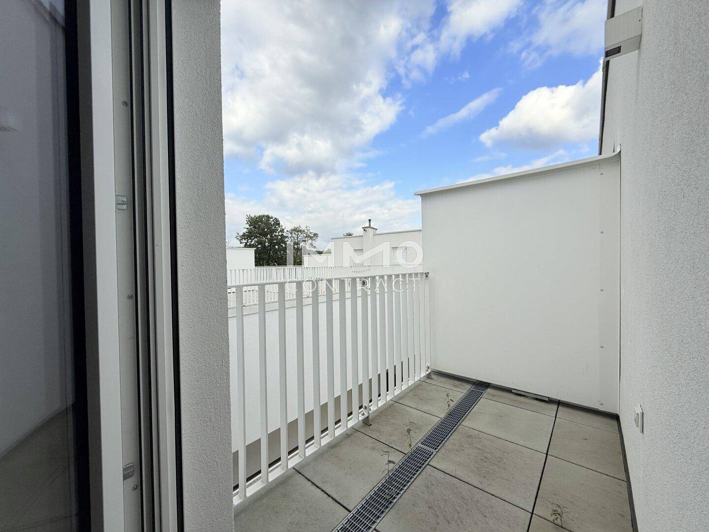 Kleiner Balkon mit weißem Geländer und Fliesenboden, ideal für einen Morgenkaffee.