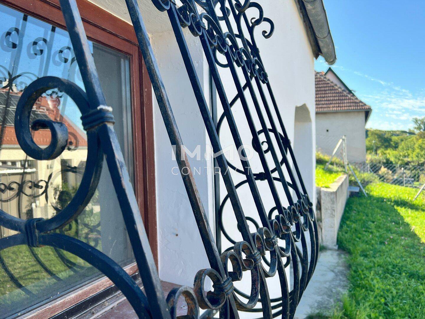 Detailansicht eines alten Fensters mit schmiedeeisernen Gittern an einem historischen Nebengebäude.