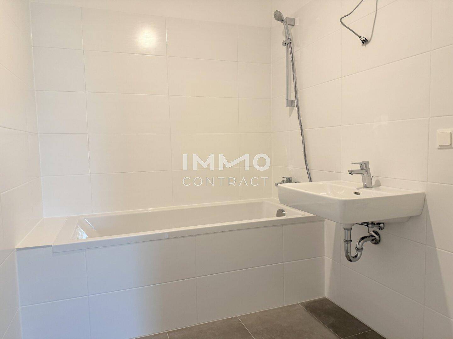 Modernes Badezimmer mit weißer Badewanne und Waschbecken, ausgestattet mit hellen Fliesen.