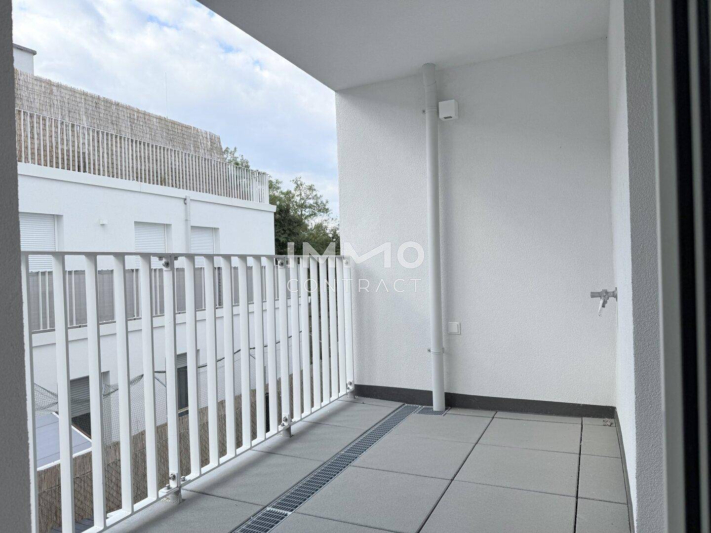 Heller Balkon mit Fliesenboden und weißem Geländer, ideal für entspannte Stunden im Freien.