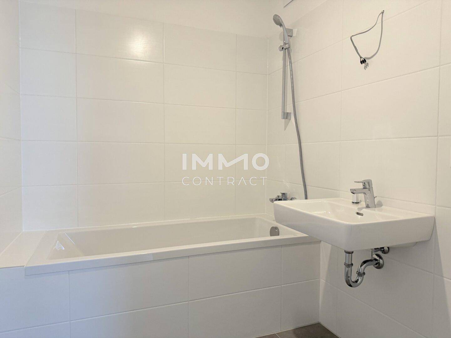 Modernes Badezimmer mit weißer Badewanne, Duscharmatur und Wandfliesen.