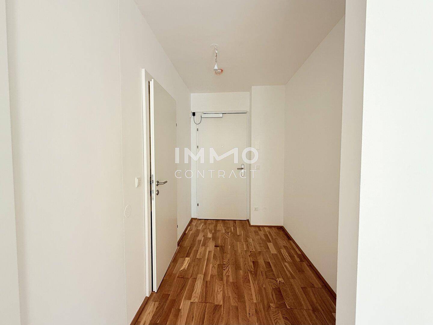 Heller Flur mit Holzboden und weißen Wänden, der zu den verschiedenen Räumen führt.