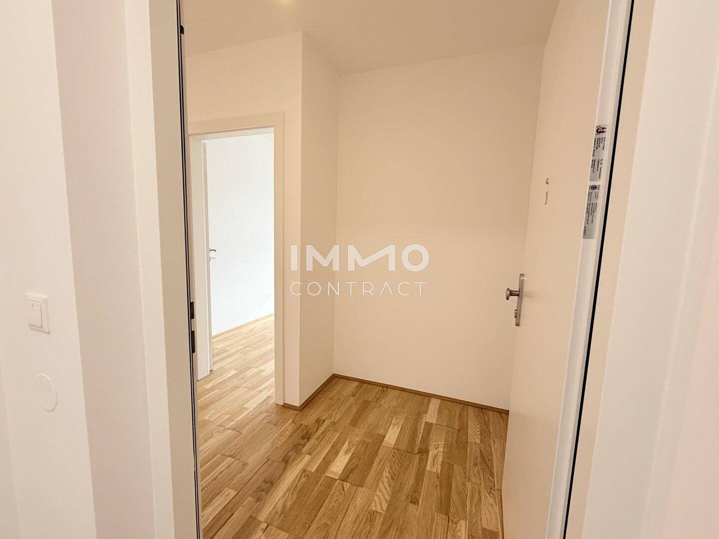 Heller Eingangsbereich mit Holzboden und weiß gestrichenen Wänden, einladend und funktional.