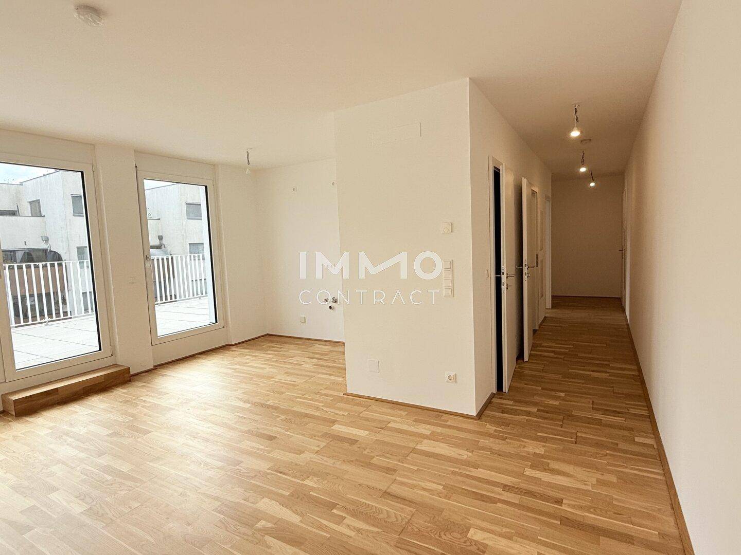 Geräumiger, heller Wohnbereich mit Holzboden und Zugang zu einem Außenbereich, ideal für offenes Wohnen.