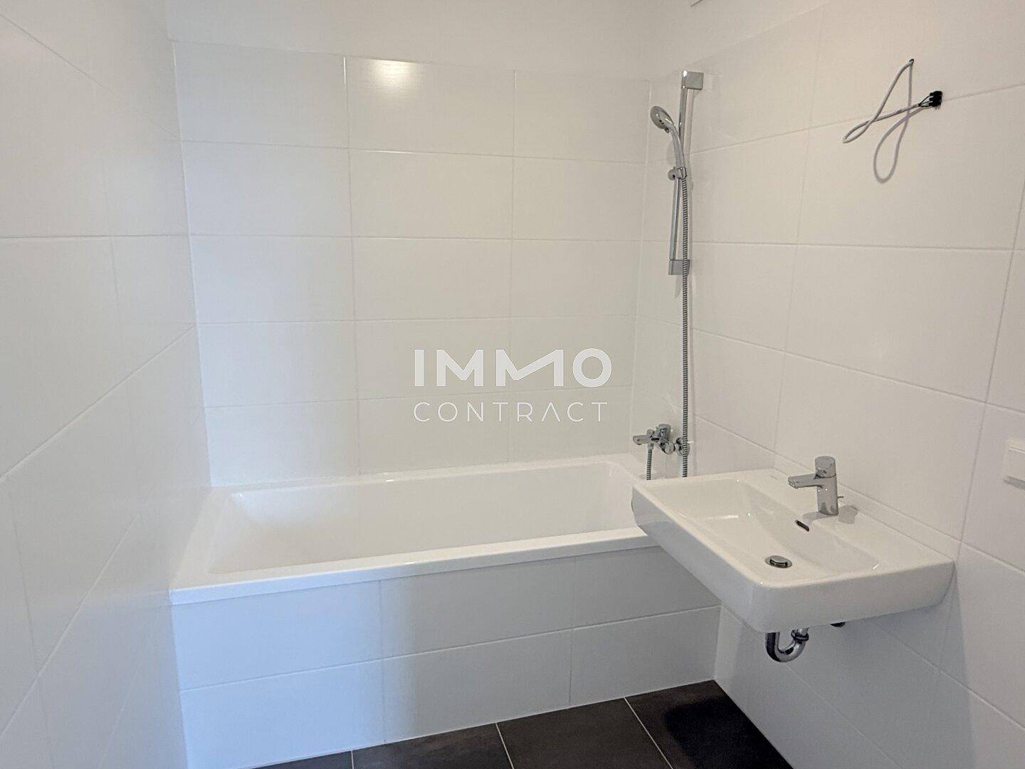 Modernes Badezimmer mit weiß gefliesten Wänden, Badewanne und Waschbecken.