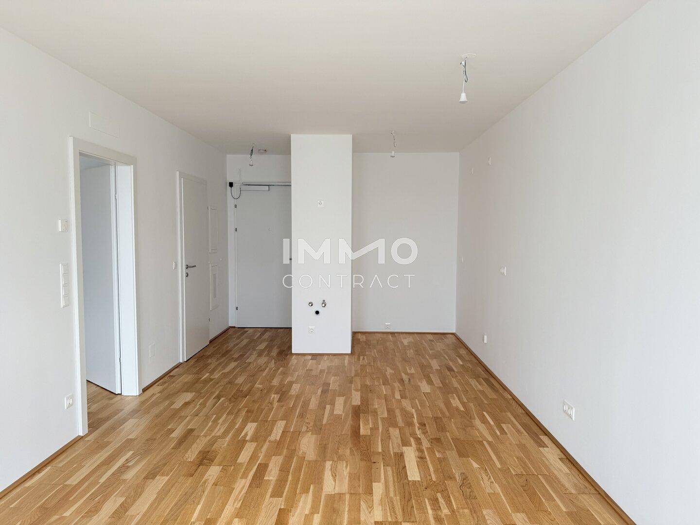 Geräumiges, unmöbliertes Zimmer mit Parkettboden und weiß gestrichenen Wänden.