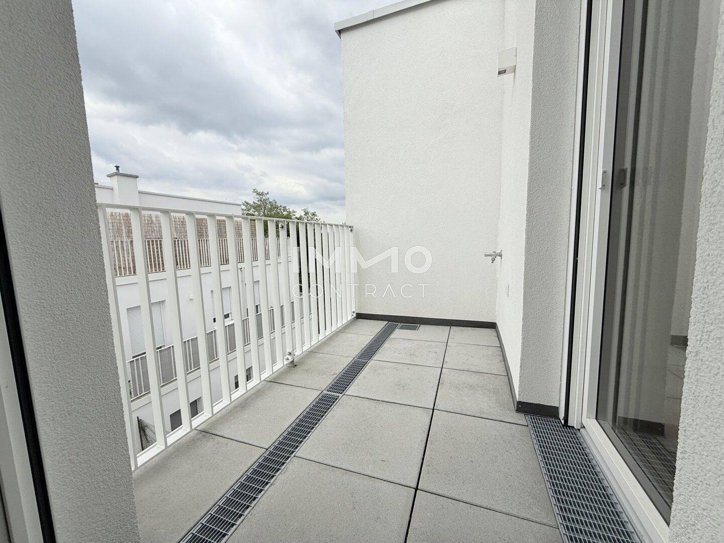 Moderner Balkon mit Metallgeländer und Blick auf umliegende Gebäude.