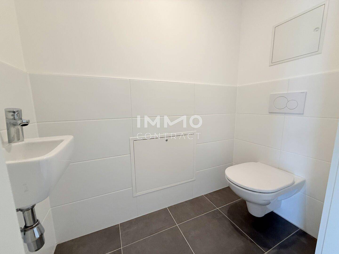 Sauberes Gäste-WC mit wandhängender Toilette und kleinem Handwaschbecken.