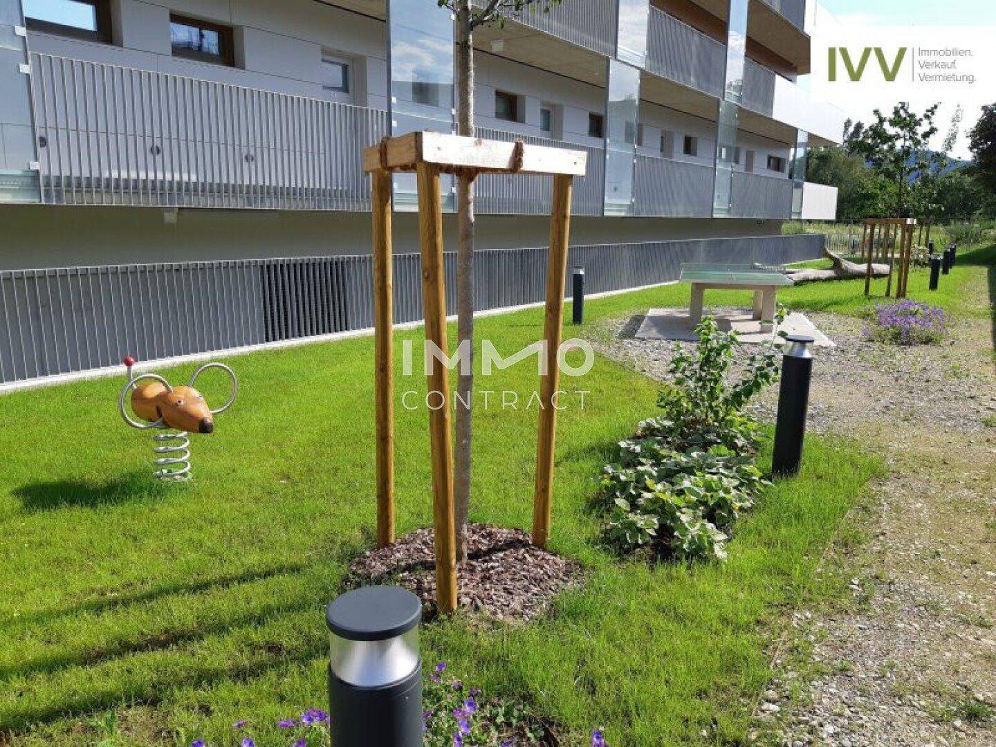 Grüne Außenanlage mit Spielgeräten, Bäumen und Rasenflächen für Kinder und Erholung.