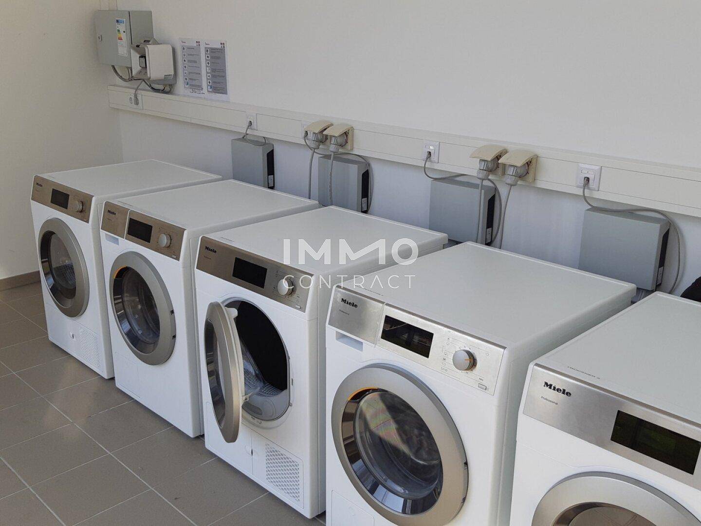 Gemeinschaftlicher Waschraum mit mehreren Waschmaschinen und Trocknern der Marke Miele.