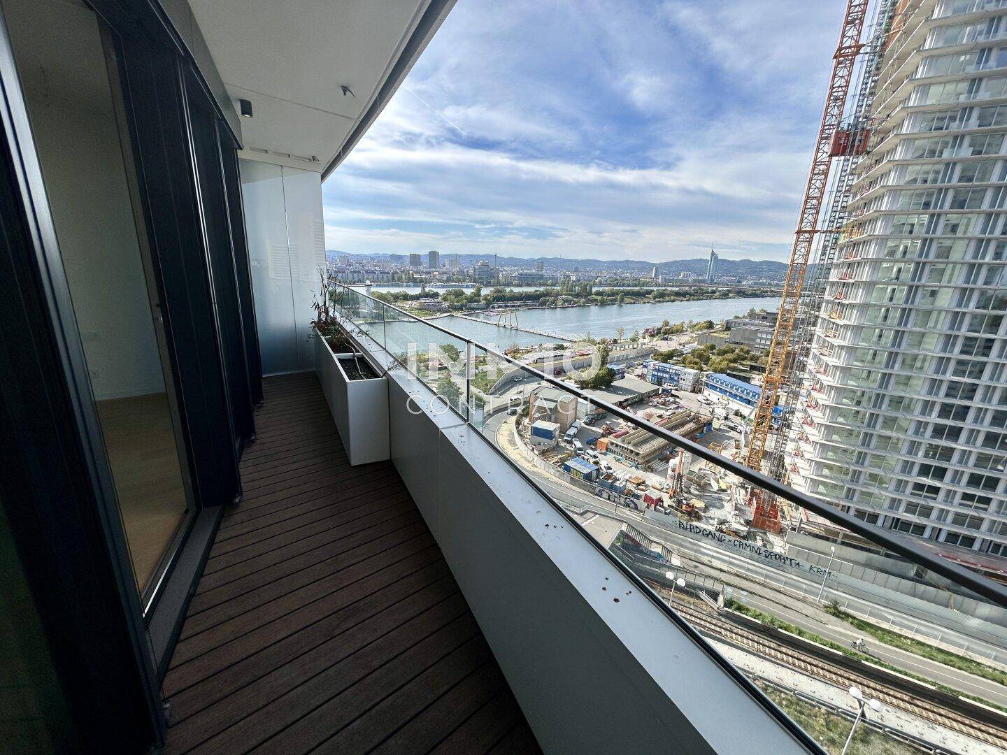 Geräumiger Balkon mit Holzboden und weitem Blick über die Stadt und den Fluss.