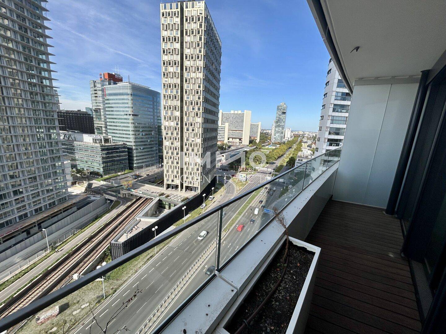 Balkon mit Holzboden und Blick auf moderne Hochhäuser und die städtische Umgebung.