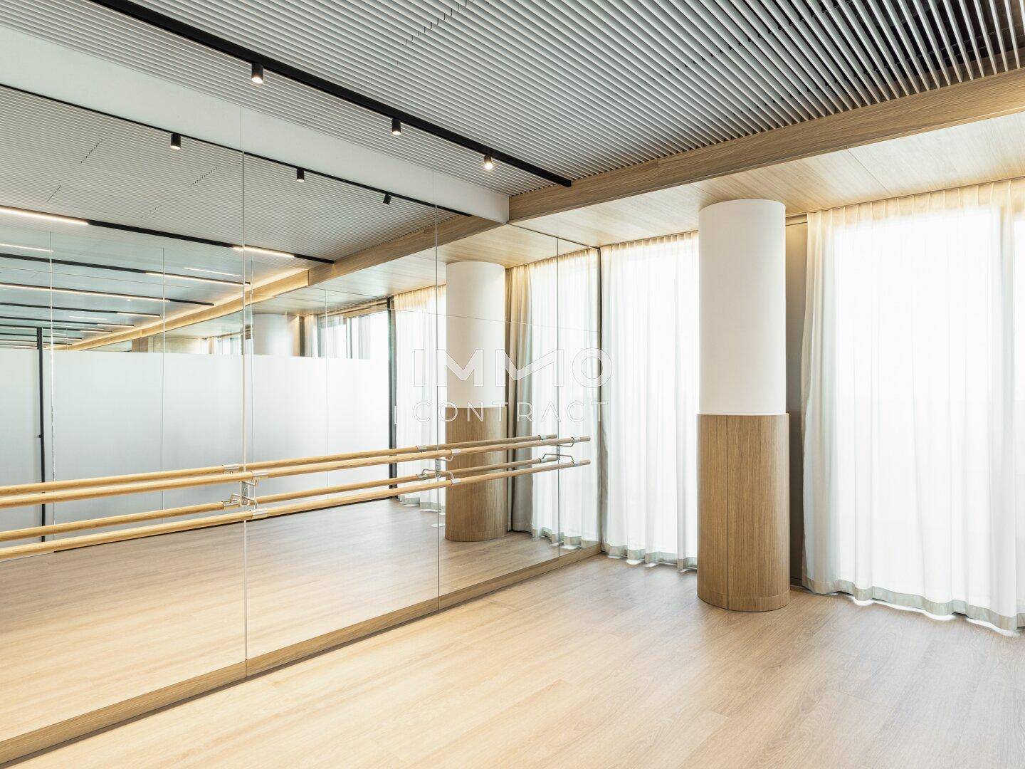 Heller Fitnessraum oder Tanzstudio mit großer Spiegelwand und Ballettstangen.