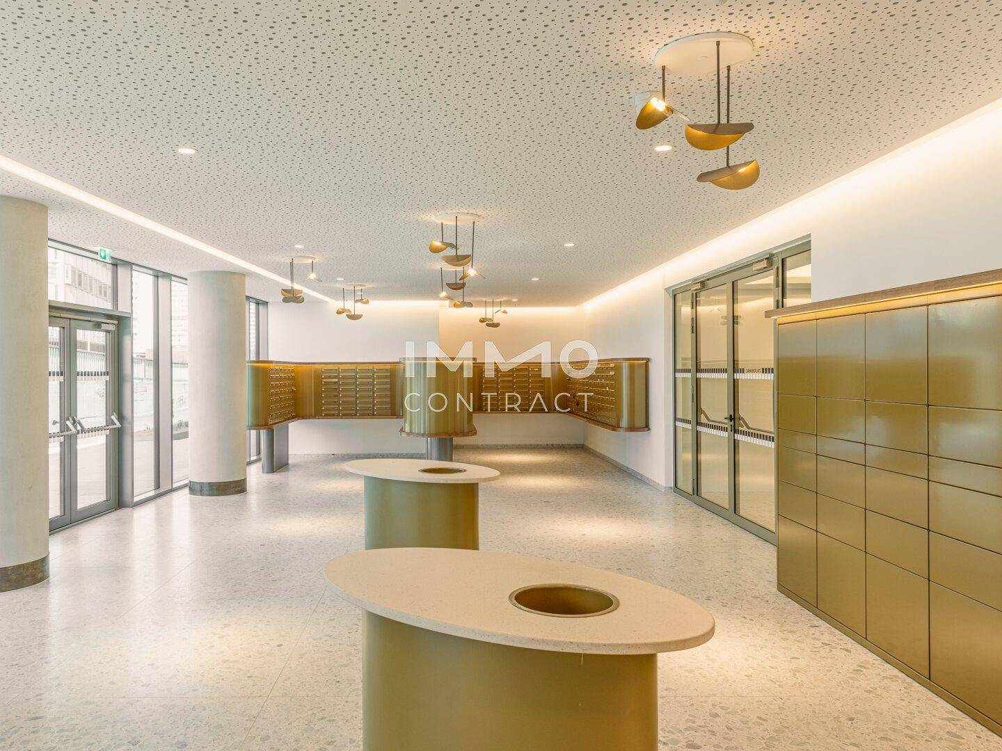 Moderner Posteingangsbereich mit goldenen Briefkästen und stilvoller Beleuchtung.